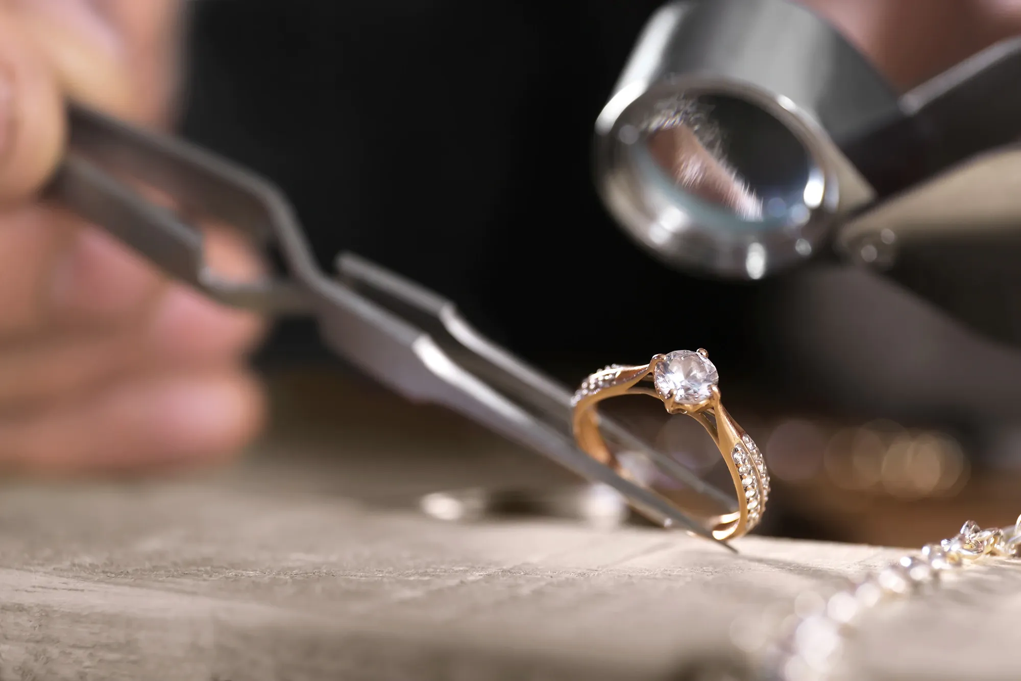 Jeweler inspecting a diamond set in a gold engagement ring.