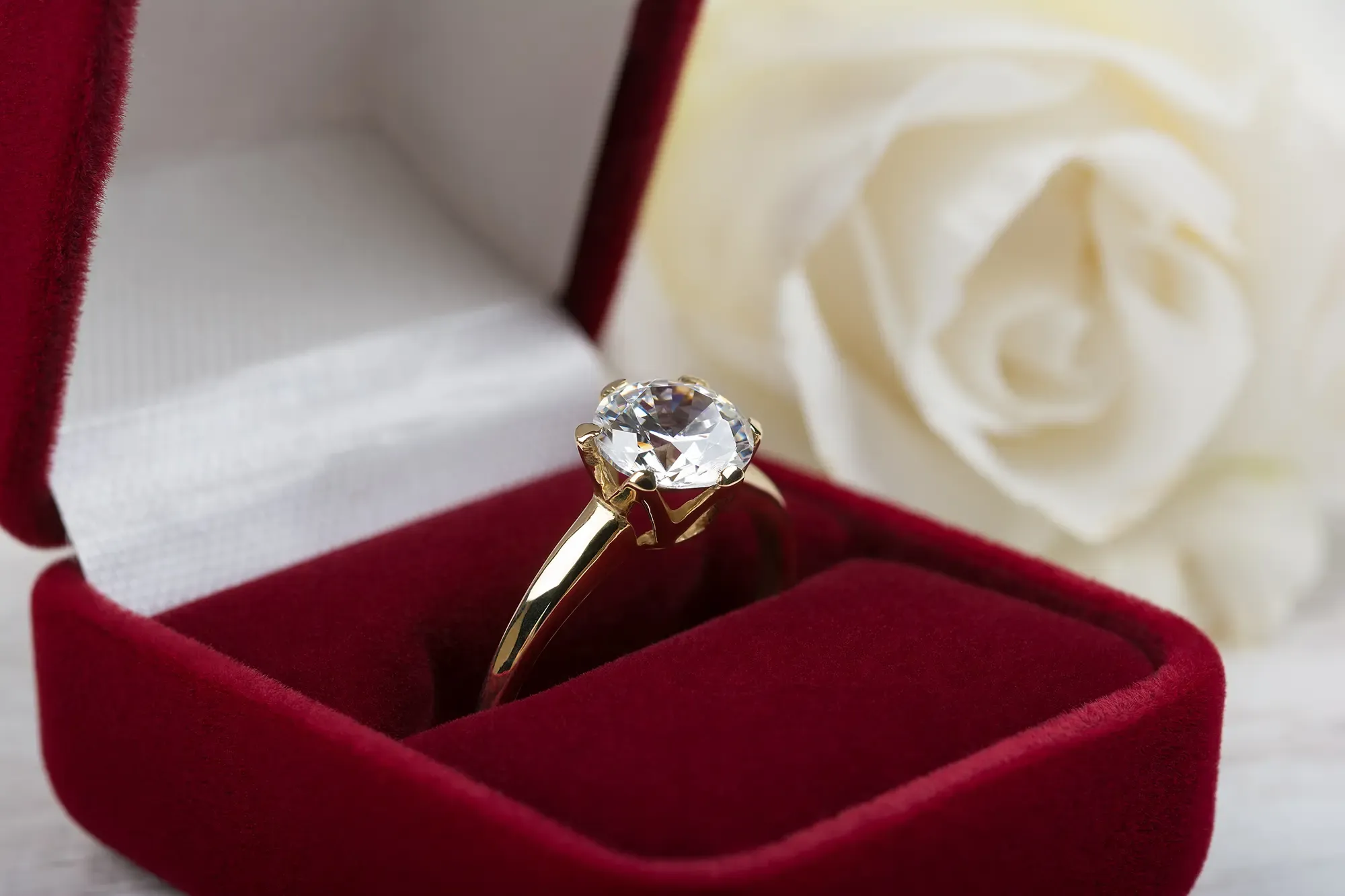 Yellow gold solitaire diamond ring in a red ring box. The stone is a round brilliant cut diamond.