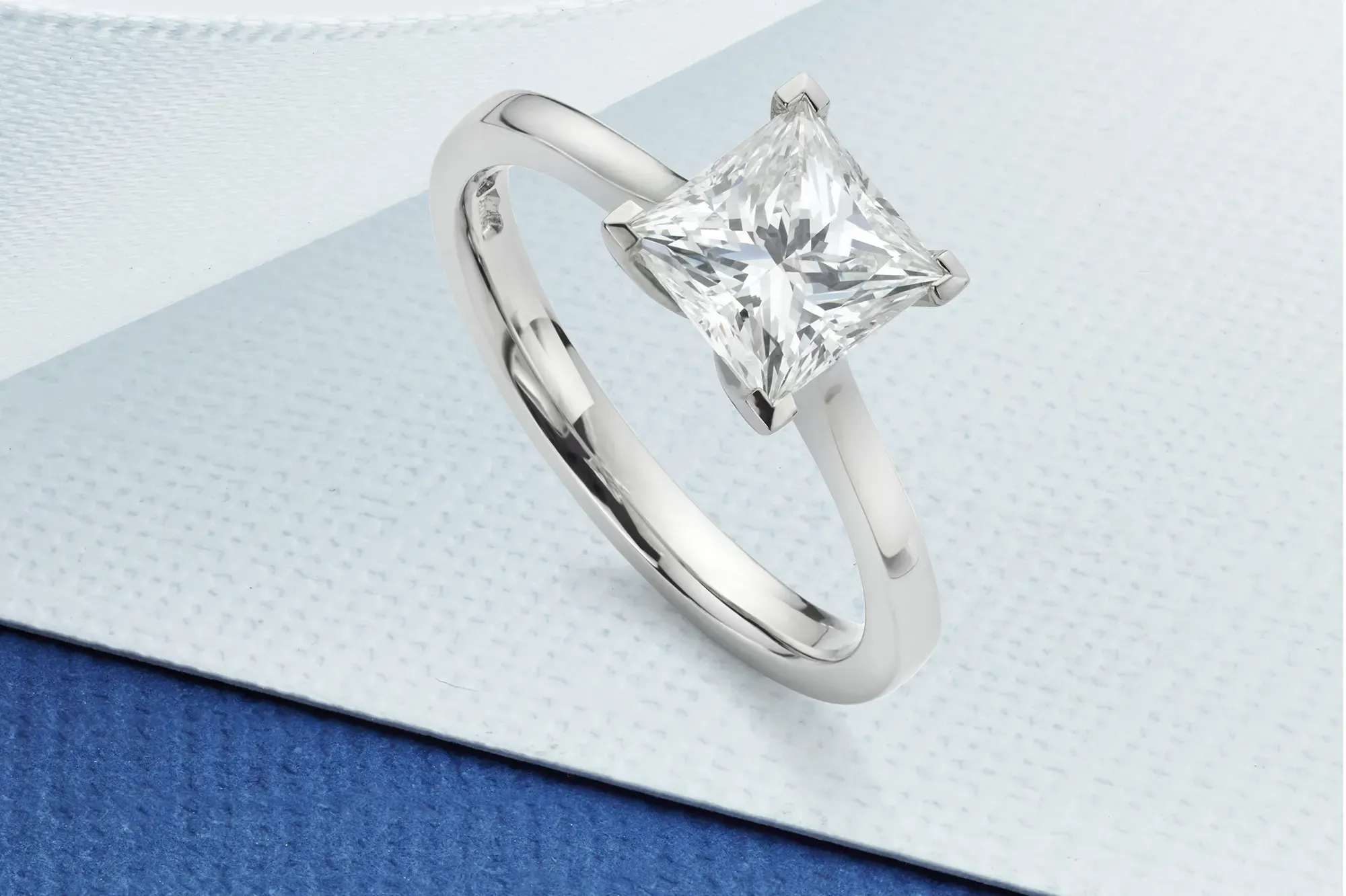 A platinum set solitaire diamond engagement ring with a princess cut diamond.